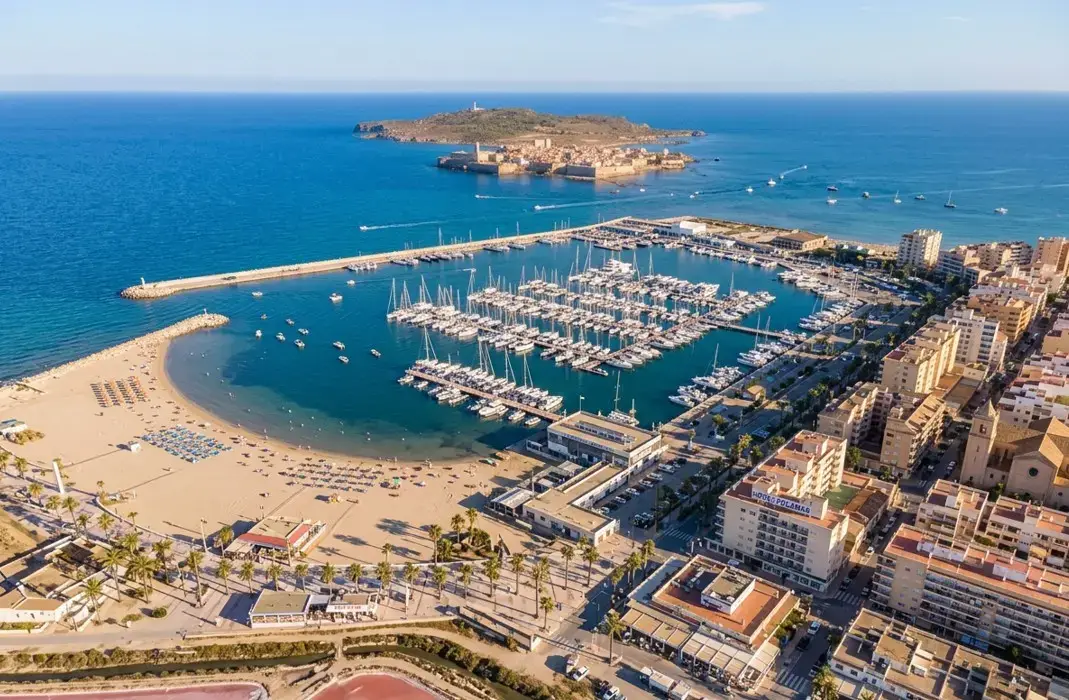 The scenic marina and beach at Santa Pola resort, a popular holiday destination reached via private taxi services from Alicante airport.