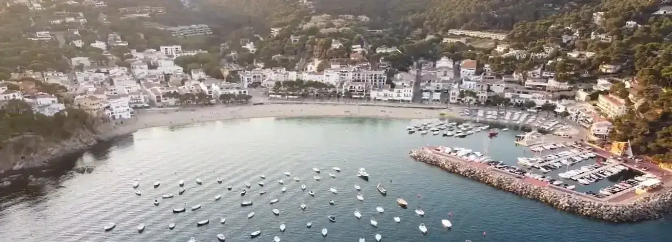 The beautiful sandy bay and beachfront of Llafranc, a premium coastal destination for Cheap Taxis private holiday airport transfers from Girona Airport.
