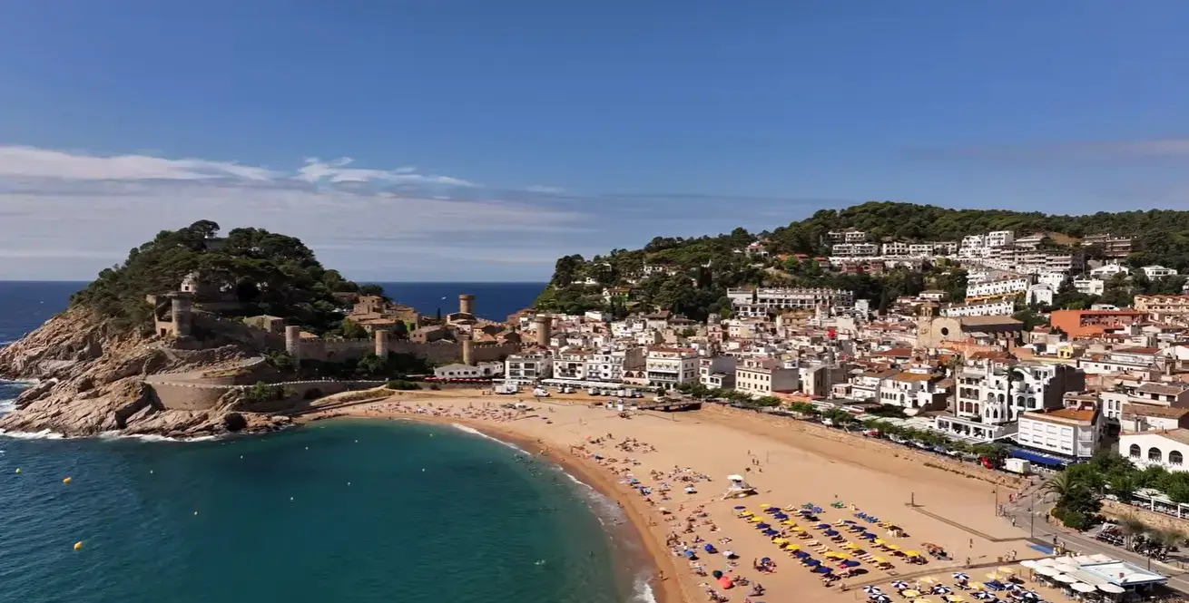 The beautiful sandy beach and iconic medieval walled fortress of Tossa de Mar, a premier holiday destination for Cheap Taxis private airport shuttle transfers from Girona Airport.