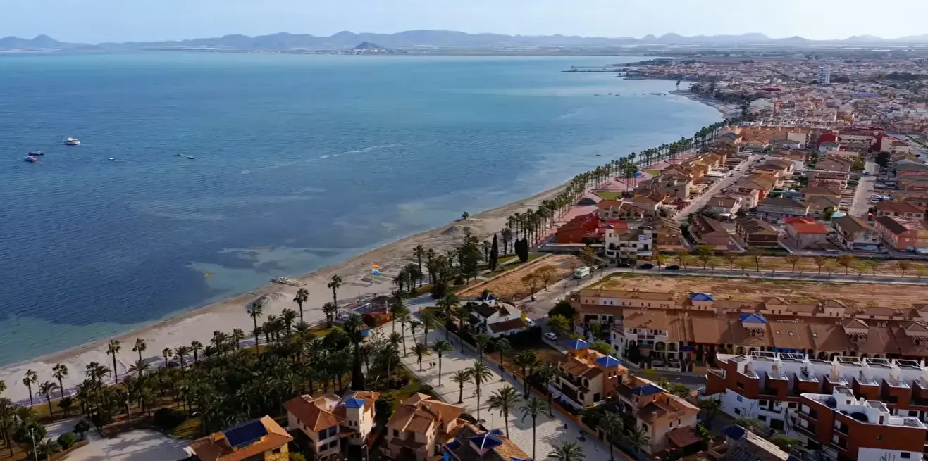 The scenic palm-lined promenade and beach at Los Alcazares resort, a popular holiday destination reached via private taxi services from Alicante airport.