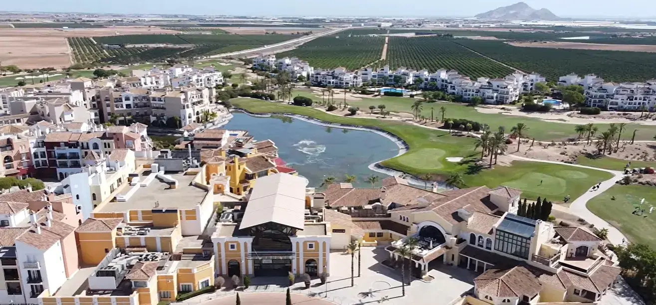 The stunning lakeside golf course and town center at La Torre Golf resort, easily accessible via private taxi services from Alicante airport.